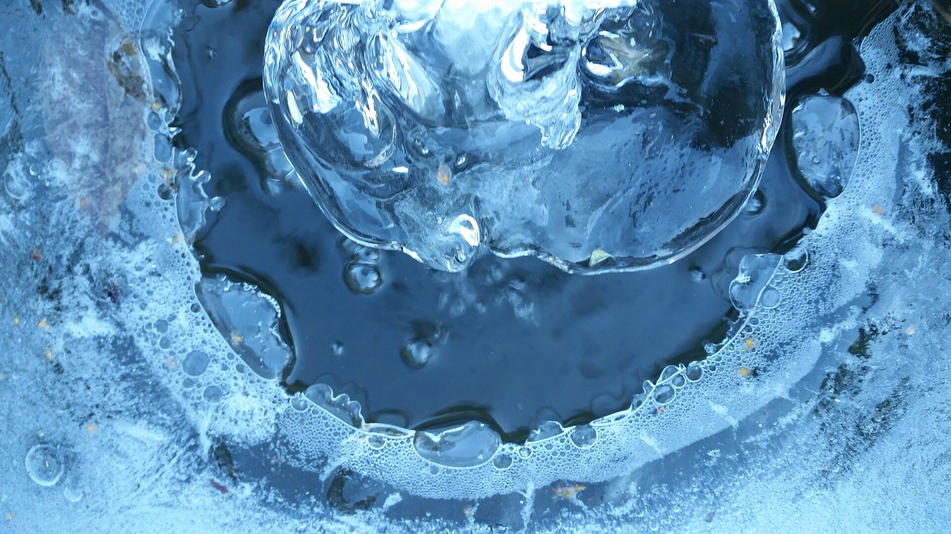 Clear ice built up around the mouth of a pipe where its water froze as it ran